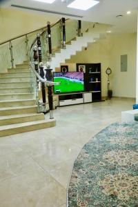 a lobby with a staircase with a television and a stair case at فيلا راحتي بدخول ذاتي in Unayzah