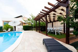 een patio met een zwembad en een houten pergola bij Villa Bistre in Radovin