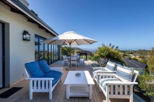 a group of chairs and an umbrella on a deck at 9 Pladda Drive in Plettenberg Bay