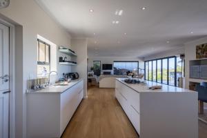 a large kitchen with white counters and a living room at 9 Pladda Drive in Plettenberg Bay