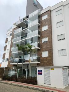 ein Apartmenthaus mit einer Parkgarage davor in der Unterkunft Apartamento na praia de Palmas à 200m do mar in Governador Celso Ramos