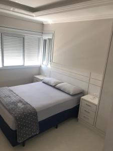 ein kleines Schlafzimmer mit einem Bett und einem Fenster in der Unterkunft Apartamento na praia de Palmas à 200m do mar in Governador Celso Ramos