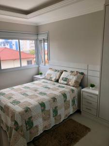 ein Schlafzimmer mit einem Bett und einem Fenster in der Unterkunft Apartamento na praia de Palmas à 200m do mar in Governador Celso Ramos