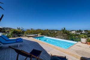 a swimming pool sitting on a wooden deck with chairs at 9 Pladda Drive in Plettenberg Bay