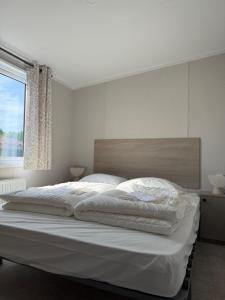 a bedroom with a large white bed with a window at TETchalet met wellness tuin in Berkhout