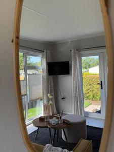 a mirror reflecting a living room with a table and a window at TETchalet met wellness tuin in Berkhout