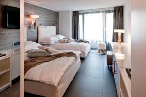 a hotel room with two beds and a television at Morosani Fiftyone - the room only Hotel in Davos