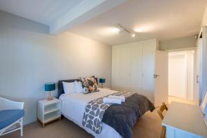 a bedroom with a bed and a table with a lamp at 9 Pladda Drive in Plettenberg Bay +12 photos