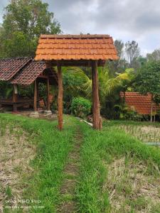 a pavilion with an orange roof in a grass field at Pengaringan Cottage Cotol in Gitgit
