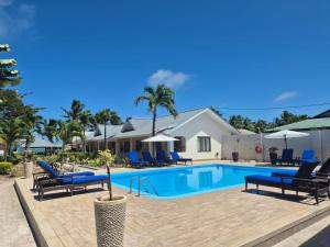 una piscina con sillas azules y una casa en Villas de Mer, en Grand'Anse Praslin