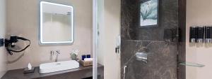 a bathroom with a shower with a sink and a mirror at Fortune Select Siliguri in Binnāguri