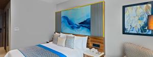 a bedroom with a large bed with a blue painting on the wall at Fortune Select Siliguri in Binnāguri