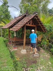 a man standing in front of a small house at Pengaringan Cottage Cotol in Gitgit