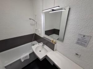 シャランにあるCit'Hôtel Le Quai 9 , ex Le Challansの洗面台と鏡のある白いバスルーム