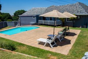 a patio with two chairs and an umbrella next to a pool at Ogans guest villa 20 Johan Meyer St, Linmeyer, Johannesburg in Johannesburg
