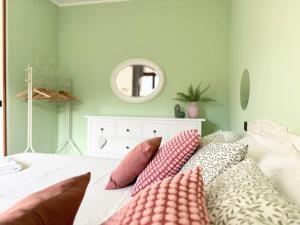 a bedroom with a bed with pink pillows and a mirror at ROSMARINO - Comodità e tranquillità con Giardino e Parcheggio in Imperia