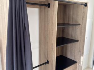 a wooden wardrobe with black shelves and a curtain at Studio neuf - entrée indépendante - sans cuisine in Nantes
