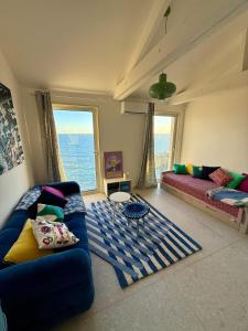 a living room with a blue couch and a large window at Casa Favelas, Vue Mer et Proche de Monaco in Cap d'Ail
