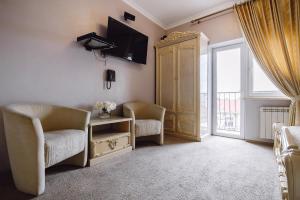 ein Zimmer mit zwei Stühlen und einem Fernseher und einem Fenster in der Unterkunft Ekaterina II Hotel in Odessa