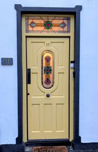 a yellow door with a stained glass window at Ivy Townhouse Derry in Derry Londonderry