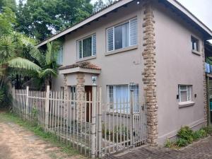 a house with a white fence in front of it at Manganese Luxury Stay in Nelspruit