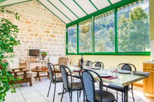 a dining room with a table and chairs and windows at L'amandier à blajoux in Montbrun