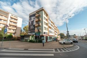 a building on the corner of a street with a person walking at Apartly - Apartament Wyszyńskiego z loggią in Szczecin
