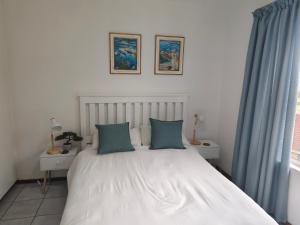 a bedroom with a large white bed with blue pillows at Laguna la crete 45,Uvongo in Uvongo Beach +25 photos