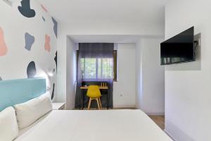 a bedroom with a white bed and a yellow chair at Hostal Carmen by gaiarooms in Salamanca