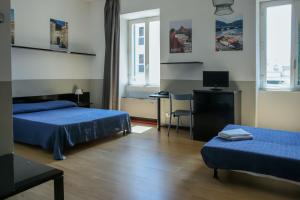 um quarto com 2 camas e uma secretária com um computador em Ostello Bello Genova em Génova