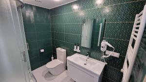 a green tiled bathroom with a toilet and a sink at Suncity Hotel & SPA in Šiauliai