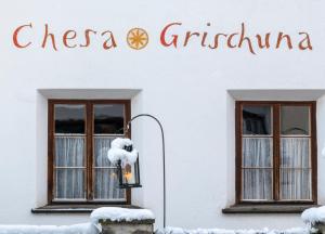a white building with two windows and a sign on it at Hotel Chesa Grischuna in Klosters +33 photos