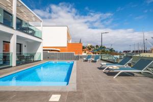 Una piscina en la azotea de un edificio con tumbonas. en Golden Home IV, en Caniçal