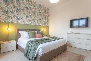 een slaapkamer met een groot bed en een tv aan de muur bij Posidonia - Free Parking & Netflix - 200m to Beach in Fiumicino