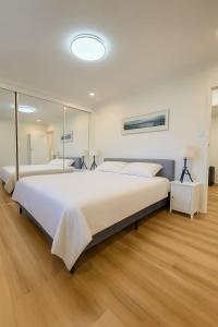 a large bedroom with a large white bed and mirrors at The Greenview Luxe Home - Hornsby in Hornsby