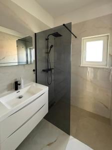 a bathroom with a white sink and a shower at Apartment Mark - Old Town of Sinj view, parking in Sinj