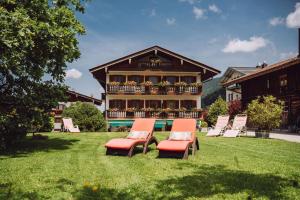 a group of chairs sitting in the grass in front of a house at Hotel garni Reiffenstuel in Rottach-Egern