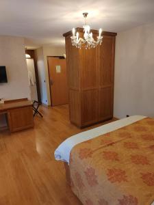 een slaapkamer met een bed en een kroonluchter bij Hôtel Restaurant Le Bretagne in Huelgoat