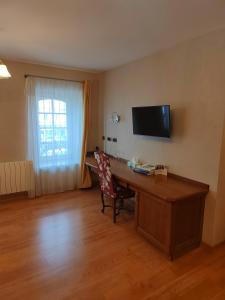 een kamer met een bureau en een televisie aan de muur bij Hôtel Restaurant Le Bretagne in Huelgoat