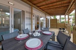 une table en bois avec des assiettes et des verres à vin sur une terrasse dans l'établissement Cozy 2 bedroom Cabin sleeps 5 in Lido di Spina, Italy - Perfect Family Retreat, à Lido di Spina 18 autres photos