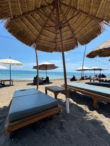 a beach with umbrellas and benches on the beach at Villa Licia - Seseh area in Balian