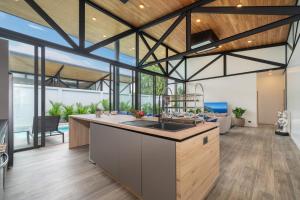 une cuisine ouverte et un salon avec des plafonds en bois dans l'établissement NEW! Sleek Design Oxygen Pool Villa 3 BR - Sunset Garden 14, à Ban Saiyuan (1)