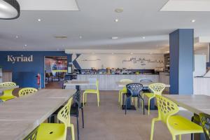 a restaurant with yellow and blue chairs and tables at Kyriad Lyon Est - Saint Bonnet De Mure in Saint-Bonnet-de-Mure +27 photos