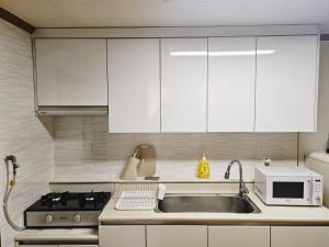 a kitchen with white cabinets and a sink and a microwave at 인천 청라3룸 인천공항 아시아드경기장 가족숙소 in So-yŏm