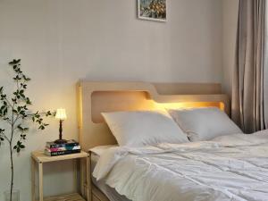 a bedroom with a white bed with a lamp on a table at 인천 청라3룸 인천공항 아시아드경기장 가족숙소 in So-yŏm