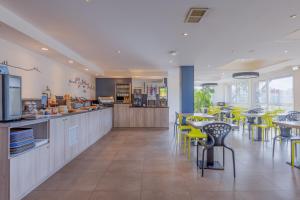 a restaurant with yellow chairs and tables in a cafeteria at Kyriad Lyon Est - Saint Bonnet De Mure in Saint-Bonnet-de-Mure