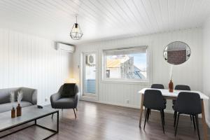 Una sala de estar blanca con una mesa y sillas. en Centrum Apartment, en Ålesund