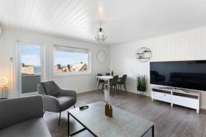 Una sala de estar con un sofá, un televisor y una mesa. en Centrum Apartment, en Ålesund