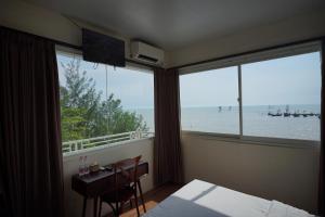 a bedroom with a desk and a view of the ocean at Vinn Villa, Coffee & Resto in Bugel