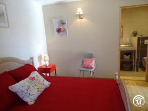 a bedroom with a red bed and a chair at Gîte à Verlac in Verlac